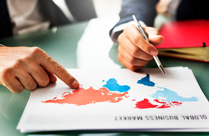 accountants pointing on a paper with the map of the world